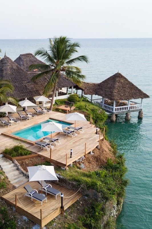 Boutique cliffside hotel deck with infinity pool, sun loungers and over-water gazebo on the Zanzibar coast.