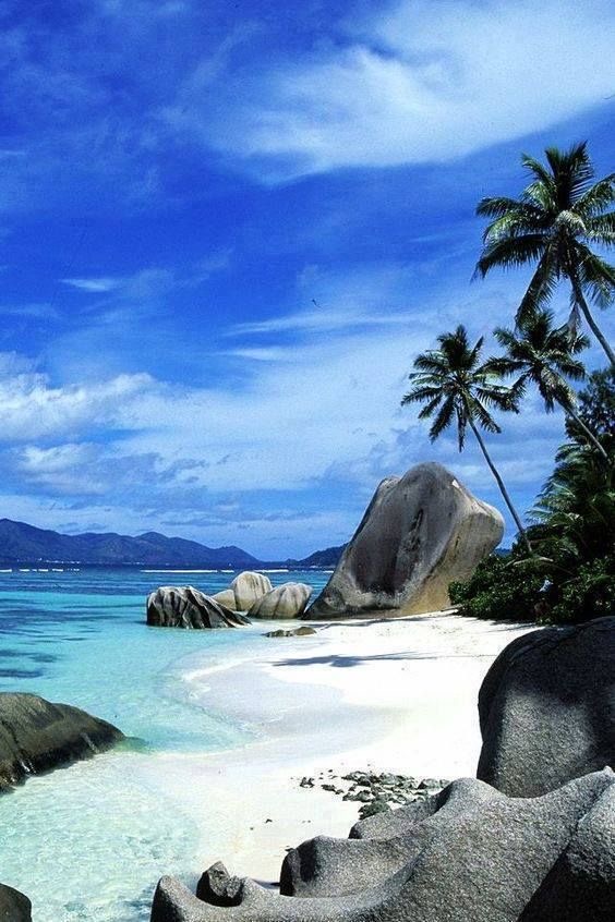 Sculpted granite boulders and coconut palms framing a secluded white-sand cove on the Indian Ocean coast.