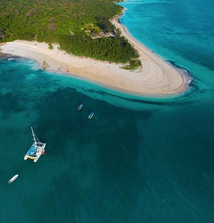Aerial view of a catamaran anchored beside a turquoise sandbank peninsula on a Zanzibar day cruise.